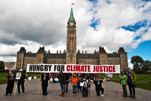 ClimateFast volunteers holding a banner in front of the Parliament Buildings that says "Hungry for Climate Change" (2015)